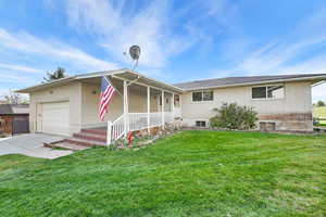 View of front facade featuring a porch, a garage, and a front yard