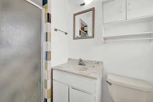 Bathroom with toilet, an enclosed shower, and vanity