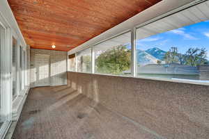 Unfurnished sunroom featuring a mountain view and wooden ceiling