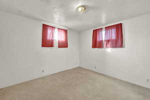 Unfurnished room with a textured ceiling and light colored carpet