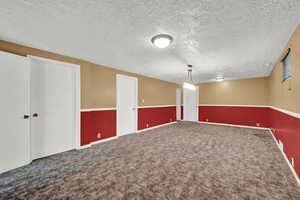 Carpeted empty room featuring a textured ceiling