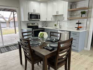 Kitchen with gray cabinets, white cabinetry, appliances with stainless steel finishes, and sink