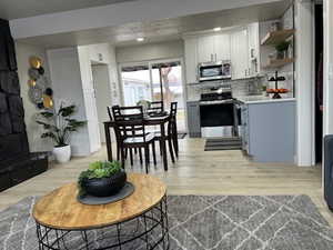 Kitchen with white cabinetry, light wood-type flooring, tasteful backsplash, and appliances with stainless steel finishes