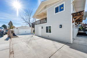 View of property exterior featuring a balcony, an outdoor structure, and a garage