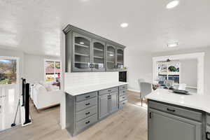 Kitchen with gray cabinets, a textured ceiling, and light hardwood / wood-style flooring