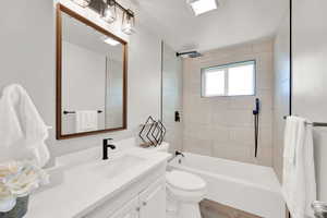 Full bathroom with toilet, vanity, tiled shower / bath combo, and hardwood / wood-style flooring