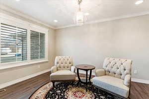 Lovely sitting room with crown molding, chandlier and plantation shutters