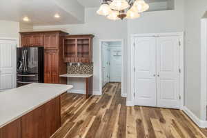 Kitchen with stainless steel refrigerator with ice dispenser, dark wood-type flooring, decorative light fixtures, and a notable chandelier