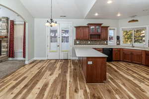 Kitchen featuring hardwood / wood-style floors, sink, a fireplace, black dishwasher, and a chandelier