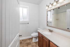 Bathroom featuring a shower, tile patterned floors, vanity, and toilet