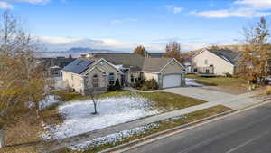 View of front of house featuring a mountain view, a front lawn, a garage, and solar panels