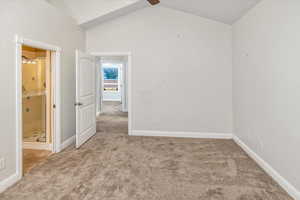 Carpeted spare room featuring vaulted ceiling