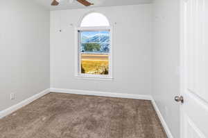 Empty room featuring ceiling fan and carpet floors