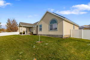 Rear view of property with solar panels and a yard