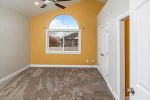 Carpeted empty room featuring ceiling fan and vaulted ceiling