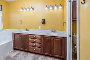 Bathroom featuring vanity, toilet, and a tub