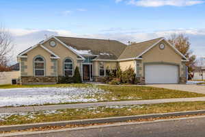 Ranch-style home featuring a garage, a front lawn, and central air condition unit