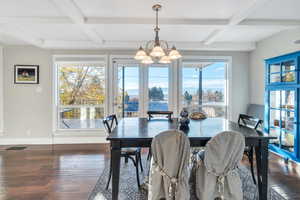 Dining area with beam ceiling, a wealth of natural light, and dark wood-type flooring