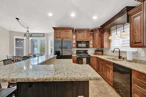 Kitchen with black appliances, a large island, a kitchen bar, and sink