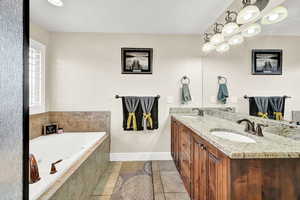 Bathroom with vanity, tile patterned floors, and tiled tub