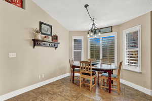 Dining area featuring a textured ceiling, a chandelier, and vaulted ceiling