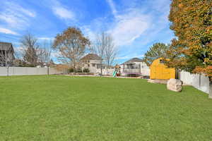 View of yard with a playground and a storage shed