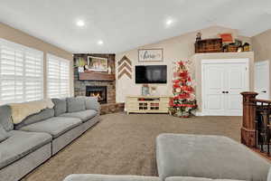 Carpeted living room featuring a fireplace and vaulted ceiling