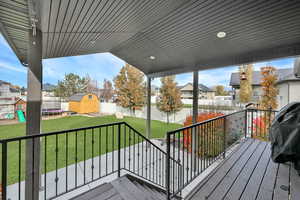 Wooden terrace with a trampoline, a storage shed, a playground, and a yard