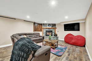 Living room featuring wood-type flooring and a stone fireplace