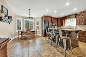 Kitchen with light stone countertops, stainless steel refrigerator, a healthy amount of sunlight, and a breakfast bar area