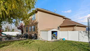 Rear view of house with a patio area, a shed, and a yard