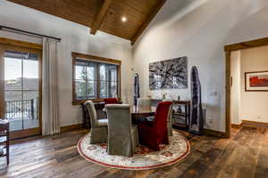 Dining space with vaulted ceiling with beams, dark hardwood / wood-style flooring, wooden ceiling, and a wealth of natural light