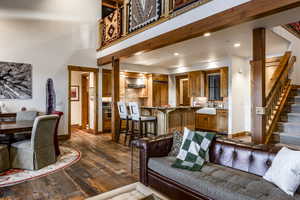 Living room with beam ceiling, sink, and dark wood-type flooring