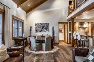 Dining area featuring beam ceiling, dark wood-type flooring, high vaulted ceiling, and wooden ceiling