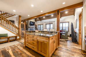 Kitchen featuring dark stone counters, a spacious island, lofted ceiling with beams, and light hardwood / wood-style floors