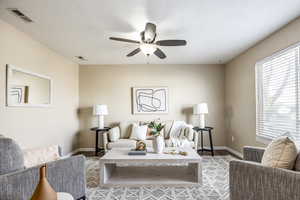 Living room featuring ceiling fan, wood-type flooring, and a textured ceiling