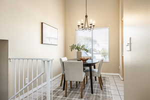 Dining room featuring tile patterned floors, a notable chandelier, and a high ceiling