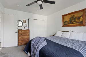 Carpeted bedroom with ceiling fan and a closet