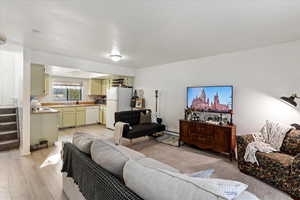 Living room with light wood-type flooring, baseboard heating, and sink