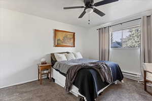 Carpeted bedroom with ceiling fan and a baseboard radiator