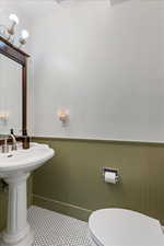 Bathroom featuring toilet, sink, and wooden walls