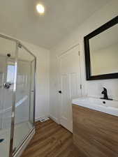 Bathroom with hardwood / wood-style floors, vanity, and an enclosed shower