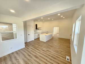 Kitchen featuring ventilation hood, a kitchen island with sink, sink, light hardwood / wood-style flooring, and white cabinetry