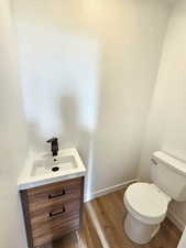 Bathroom with toilet, vanity, and hardwood / wood-style flooring