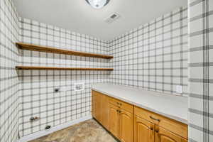 Washroom with electric dryer hookup, cabinets, a textured ceiling, and hookup for a washing machine