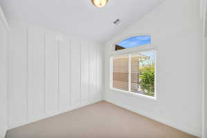 Empty room featuring light carpet and vaulted ceiling