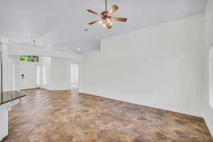 Unfurnished living room featuring ceiling fan and vaulted ceiling