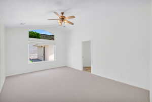 Empty room featuring ceiling fan, carpet floors, and vaulted ceiling