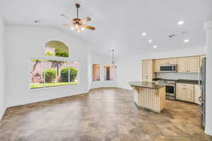 Kitchen featuring high vaulted ceiling, plenty of natural light, a kitchen island, and appliances with stainless steel finishes