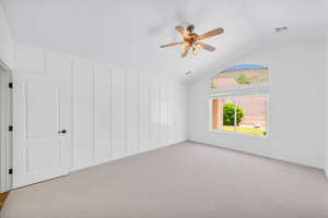 Carpeted empty room with ceiling fan and lofted ceiling